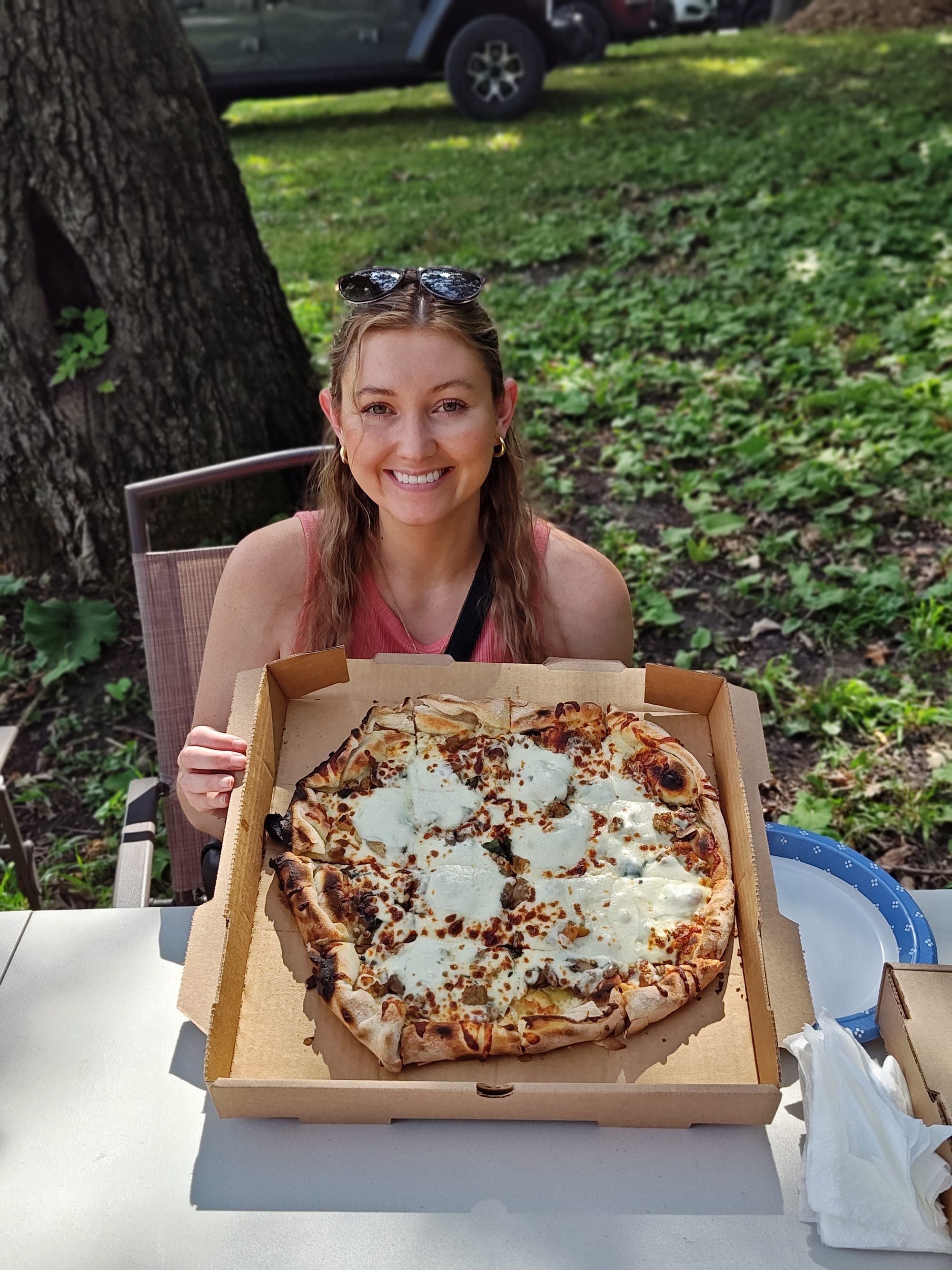 smiling woman holding a whole, mushroom pizza