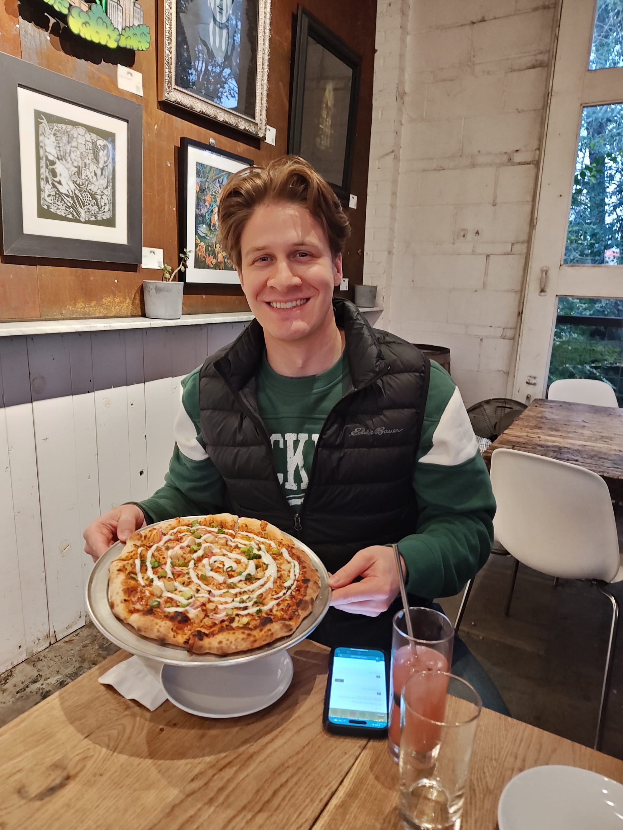smiling man holding a BBQ pizza