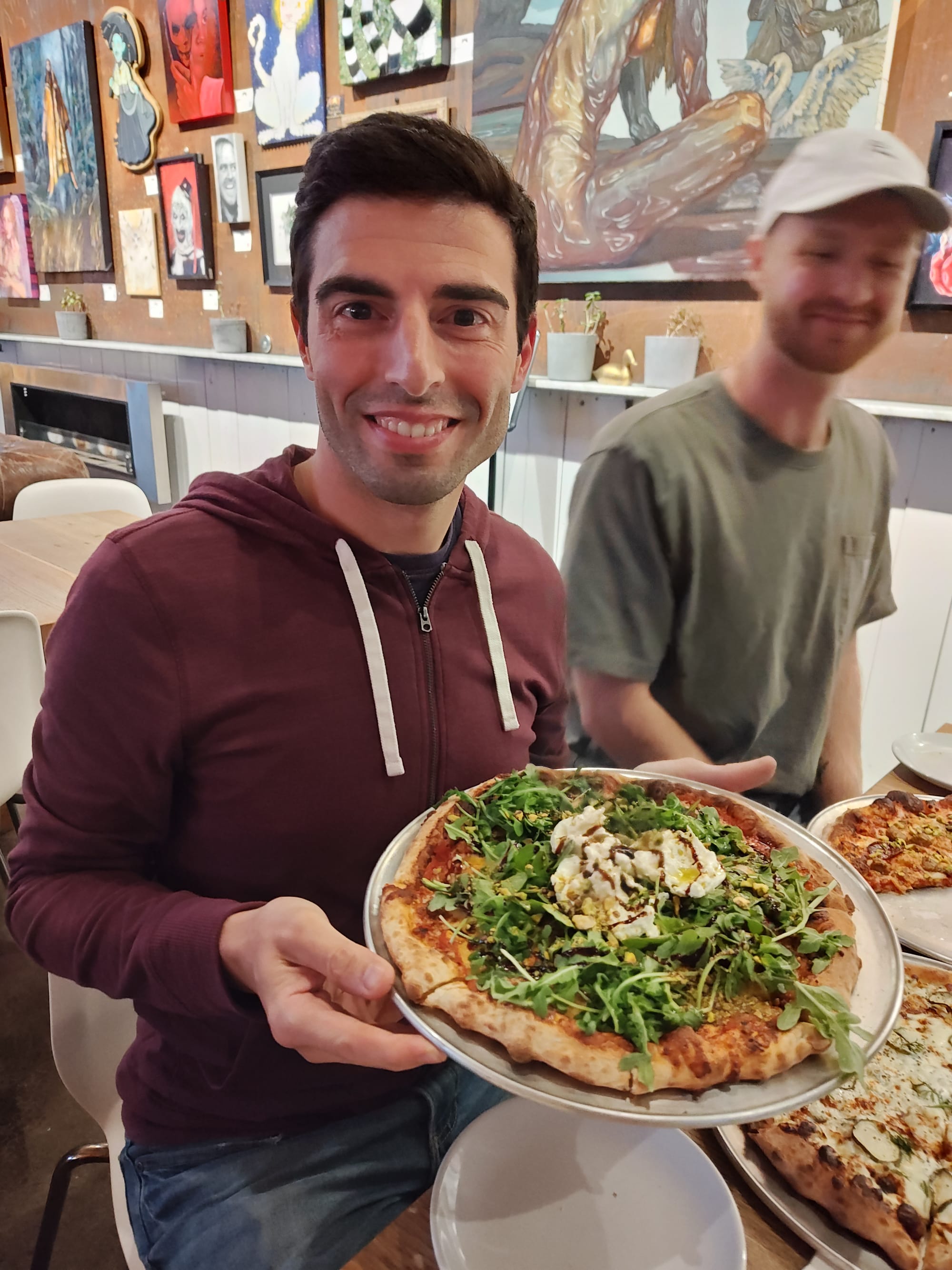 smiling man holding a peach pizza