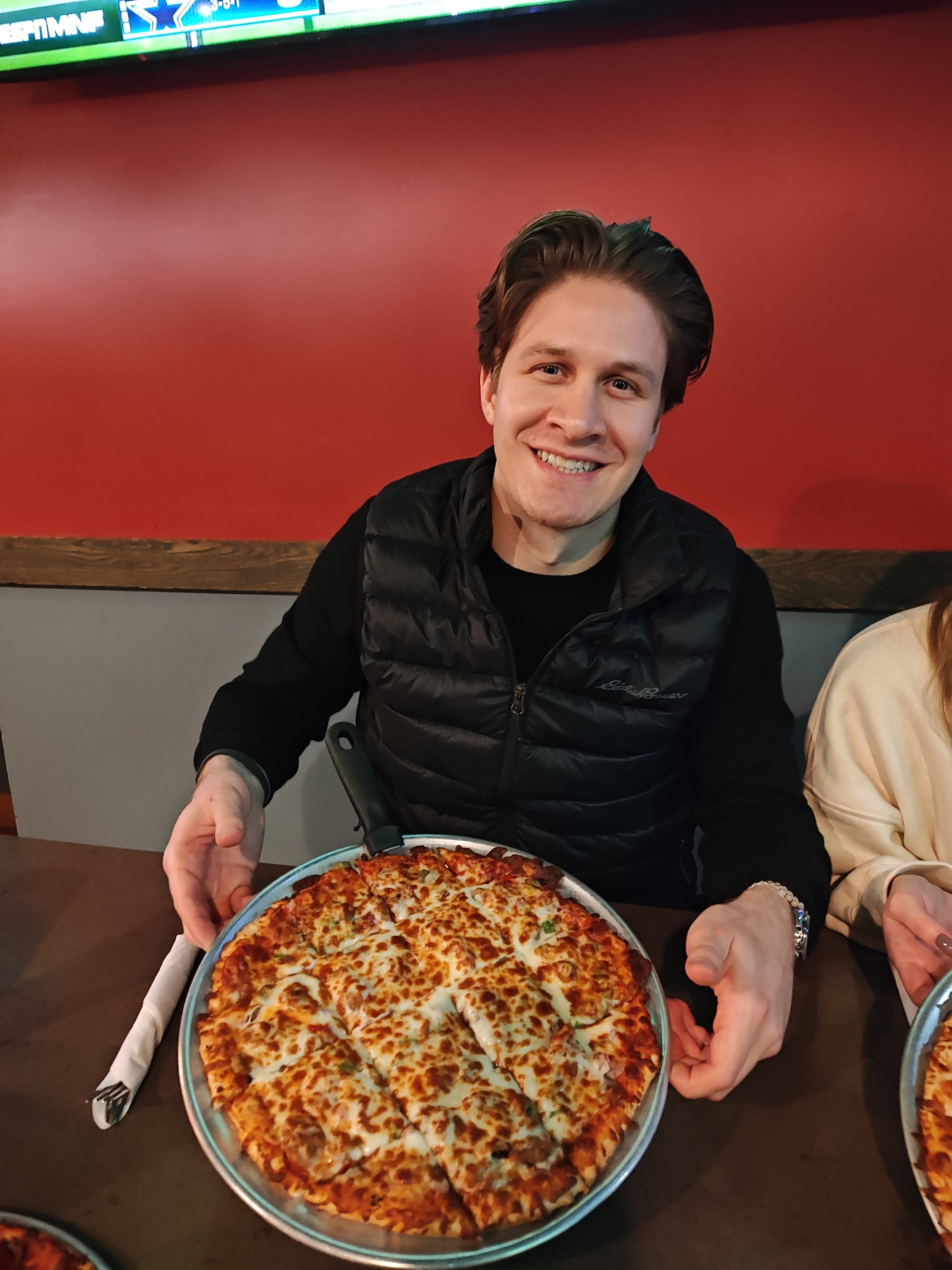 man holding a supreme pizza