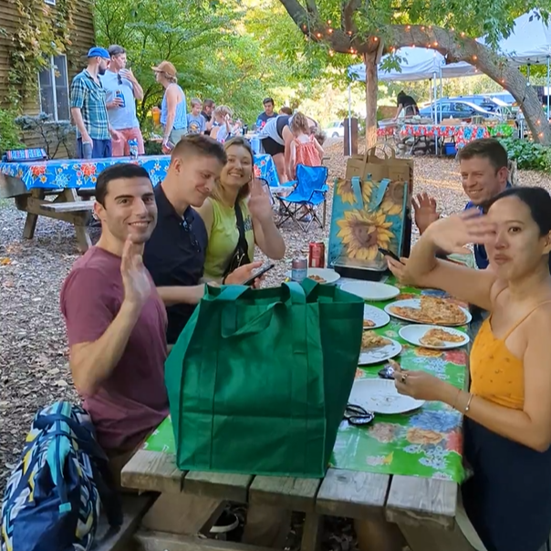 people sitting at a picnic table eating pizz